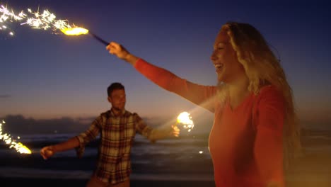 Couple-dancing-with-sparklers-on-beach-at-dusk-4k