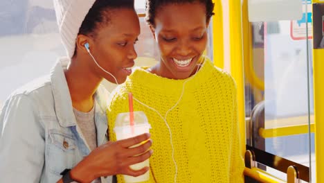 Twin-sisters-listening-music-on-mobile-phone-in-the-bus-4k
