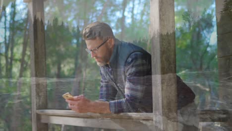 Man-leaning-on-a-porch-while-texting-on-his-phone