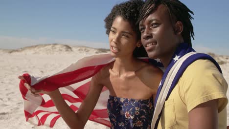 Couple-wrapped-in-American-flag-sitting-together-on-the-beach-4k