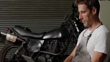 Male-mechanic-using-laptop-in-motorbike-repair-garage-4k