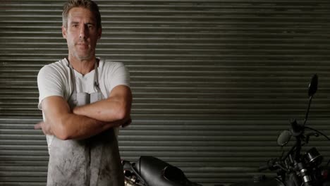 Male-mechanic-wearing-apron-in-motorbike-repair-garage-4k