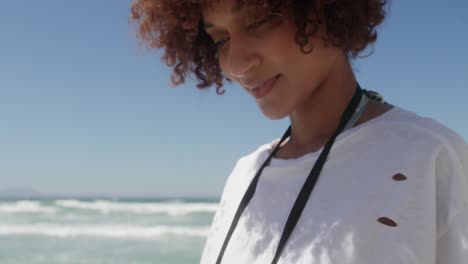 Vorderansicht-Einer-Afroamerikanischen-Frau,-Die-Ihr-Mobiltelefon-Am-Strand-Benutzt,-4k