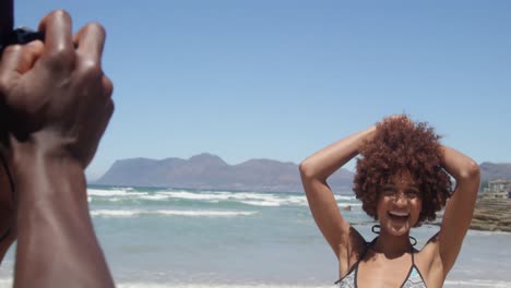 Young-African-american-man-taking-pictures-of-woman-with-digital-camera-on-the-beach-4k