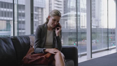 Businesswoman-talking-on-mobile-phone-in-the-lobby-at-office-4k