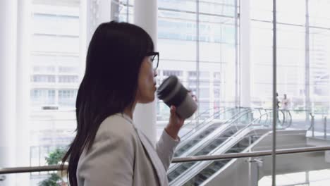 Businesswoman-talking-on-mobile-phone-and-walking-in-the-lobby-at-office-4k