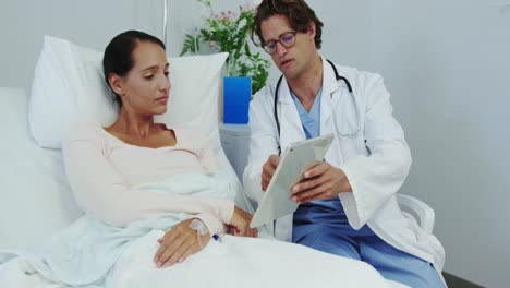 Vista-Frontal-De-Un-Médico-Caucásico-Y-Una-Paciente-Discutiendo-Sobre-Una-Tableta-Digital-En-La-Sala-4k