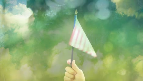 Hand-holding-American-flag-in-the-forest