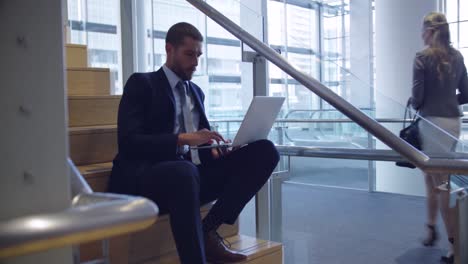 Businessman-using-laptop-on-stairs-in-the-office-4k
