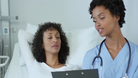 Vista-Frontal-De-Una-Doctora-Afroamericana-Hablando-Con-Una-Paciente-En-La-Sala-Del-Hospital