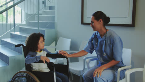 Vista-Frontal-De-Una-Doctora-Caucásica-Interactuando-Con-Un-Niño-Discapacitado-En-El-Pasillo-Del-Hospital-4k