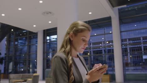 Businesswoman-using-mobile-phone-in-the-lobby-at-office-4k