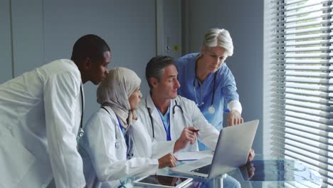 Front-view-of-Multi-ethnic-doctors-discussing-over-laptop-in-hospital