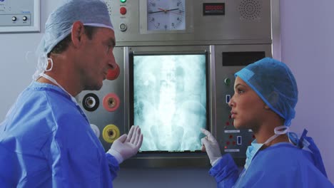 Seitenansicht-Von-Multiethnischen-Ärzten,-Die-über-Einen-Röntgenbericht-Auf-Einem-Leuchtkasten-Im-Krankenhaus-Diskutieren