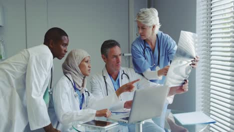 Vorderansicht-Multiethnischer-Ärzte,-Die-Im-Krankenhaus-über-Einen-Röntgenbericht-Diskutieren