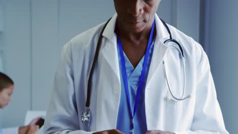 Nahaufnahme-Eines-Afroamerikanischen-Männlichen-Arztes,-Der-Im-Krankenhaus-Ein-Mobiltelefon-Benutzt,-4K