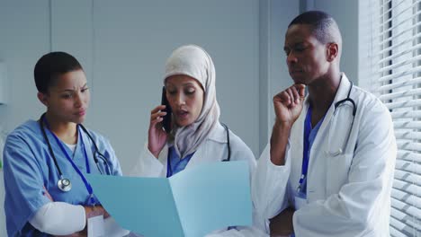 Front-view-of-Middle-East-female-doctor-talking-on-mobile-phone-with-her-colleagues-in-hospital