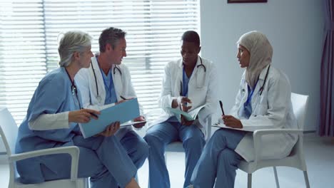 Vorderansicht-Multiethnischer-Ärzte,-Die-Im-Krankenhaus-über-Krankenakten-Diskutieren