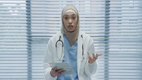 Young-female-doctor-using-tablet-and-talking-to-camera-4k