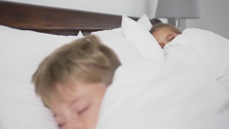 Siblings-sleeping-on-bed-in-bedroom-at-comfortable-home-4k