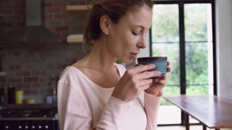 Woman-drinking-coffee-in-kitchen-at-comfortable-home-4k
