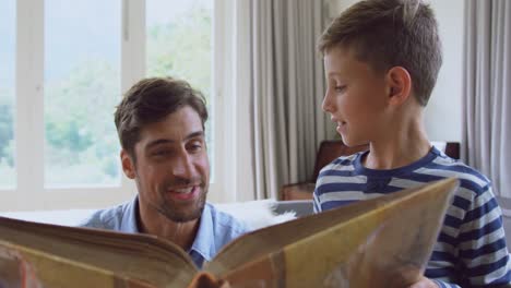 Father-and-son-reading-story-book-at-home-4k