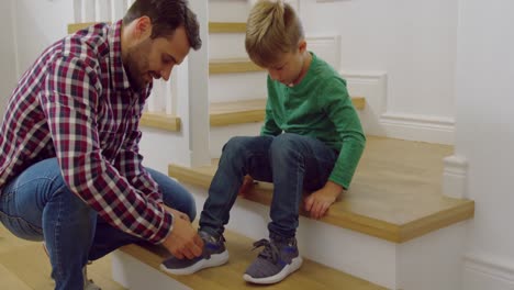 Father-tying-his-sons-shoelaces-in-a-comfortable-home-4k