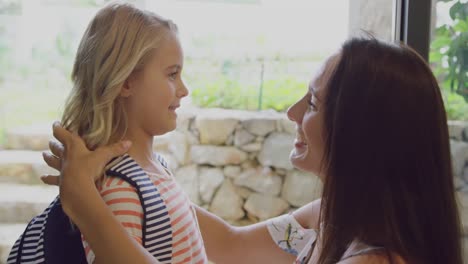 Daughter-embracing-her-mother-before-leaving-school-at-door-in-home-4k