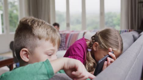 Siblings-using-mobile-phone-on-sofa-in-a-comfortable-home-4k