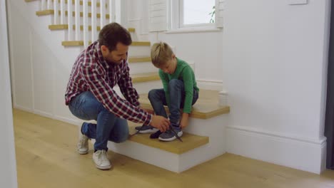 Father-tying-his-sons-shoelaces-in-a-comfortable-home-4k