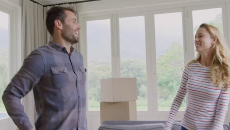 Couple-keeping-down-cardboard-box-and-embracing-each-other-in-new-home-4k