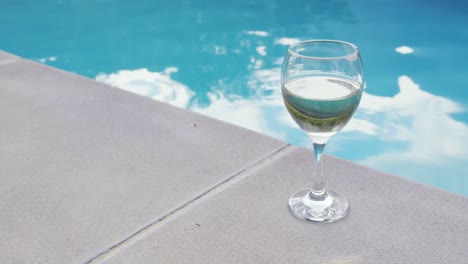 Drink-in-glass-near-swimming-pool-in-the-backyard-4k