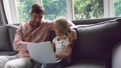 Father-and-daughter-using-laptop-on-sofa-at-home-4k