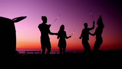 Young-adult-friends-having-fun-on-the-beach-at-night-with-sparklers-4k