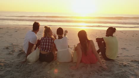 Young-adult-friends-relaxing-on-the-beach-at-sunset-4k