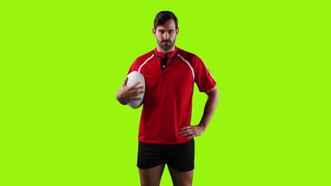 Professional-rugby-player-standing-and-holding-a-ball-on-green-background-4k