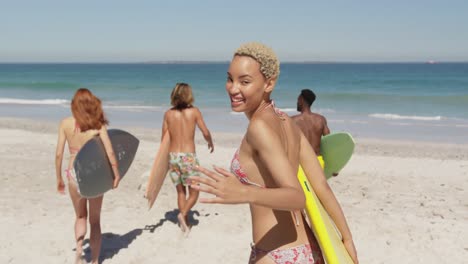 Young-adult-friends-at-the-beach-carrying-surfboards-4k