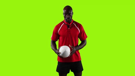 Professional-rugby-player-standing-and-pointing-with-a-ball-on-green-background-4k