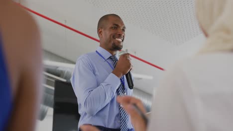 Male-speaker-addressing-applauding-audience-at-a-business-seminar