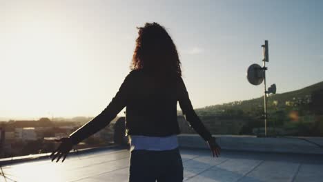 Fashionable-young-woman-on-urban-rooftop-with-arms-outstretched