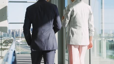 Two-young-business-people-walking-in-a-modern-office