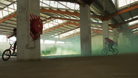 BMX-Fahrer-In-Einem-Leeren-Lagerhaus-Mit-Rauchgranate