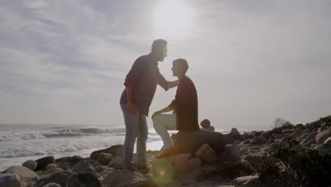 Caucasian-couple-enjoying-free-time-by-sea-on-sunny-day,-man-kissing