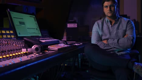 Male-sound-engineer-sitting-at-a-mixing-desk
