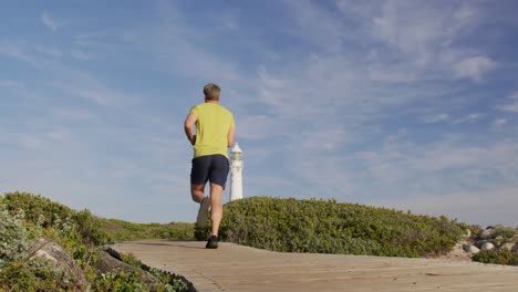 Caucasian-man-enjoying-free-time-by-sea-on-sunny-day-running-path
