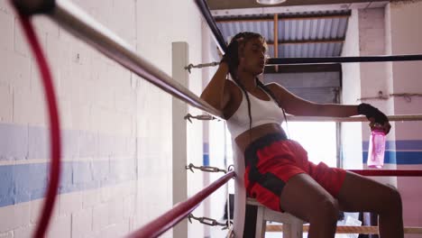 Mixed-race-woman-resting-in-boxing-gym