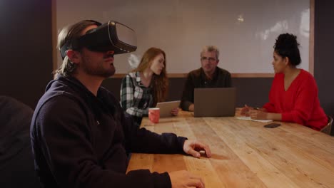 Man-wearing-VR-headset-with-colleagues-working-in-creative-office