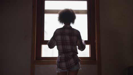 Mixed-race-woman-opening-the-window-at-home