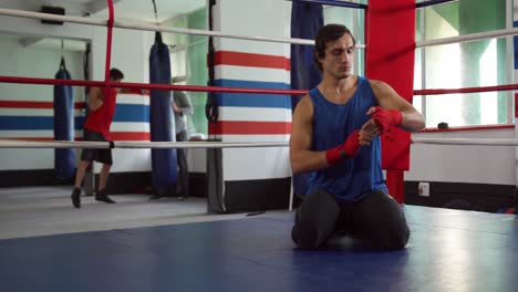 Mixed-race-man-wrapping-hands-in-boxing-ring