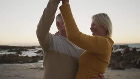 Happy-senior-couple-dancing-at-beach